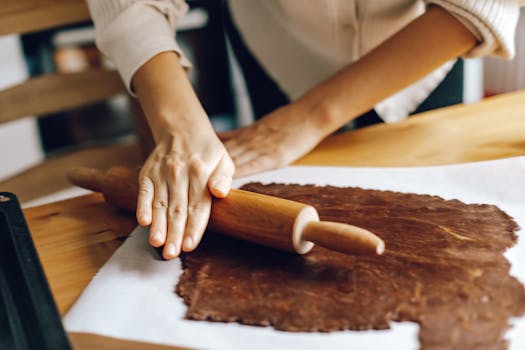 A woman skillfully rolling dough for homemade pastries in a cozy kitchen setting.
