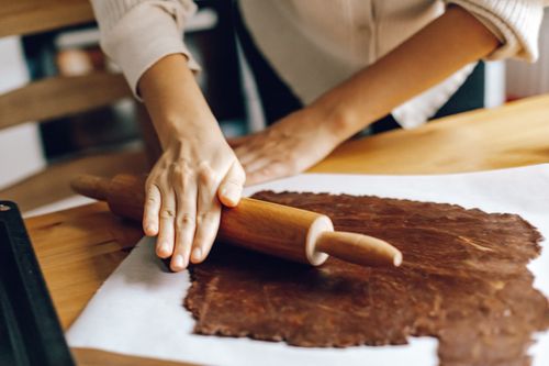 Free A woman skillfully rolling dough for homemade pastries in a cozy kitchen setting. Stock Photo