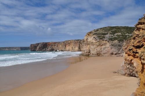 Brown Sand Beach Near Green Mountain Under Blue Sky