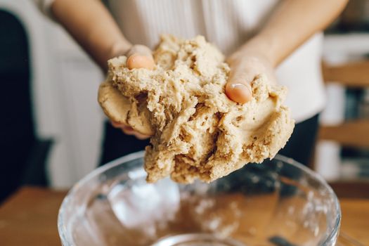 Person kneading dough in a glass bowl during a baking process at home.