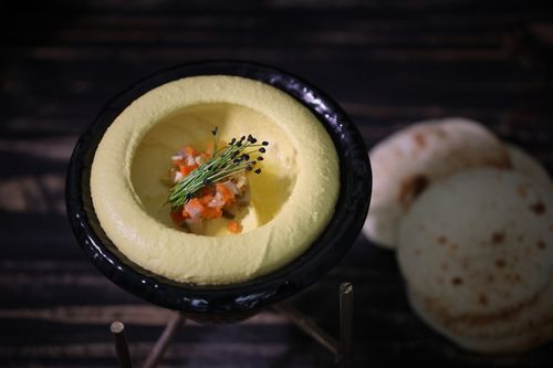 Free Gourmet hummus elegantly presented in a black bowl garnished with herbs and vegetables. Stock Photo