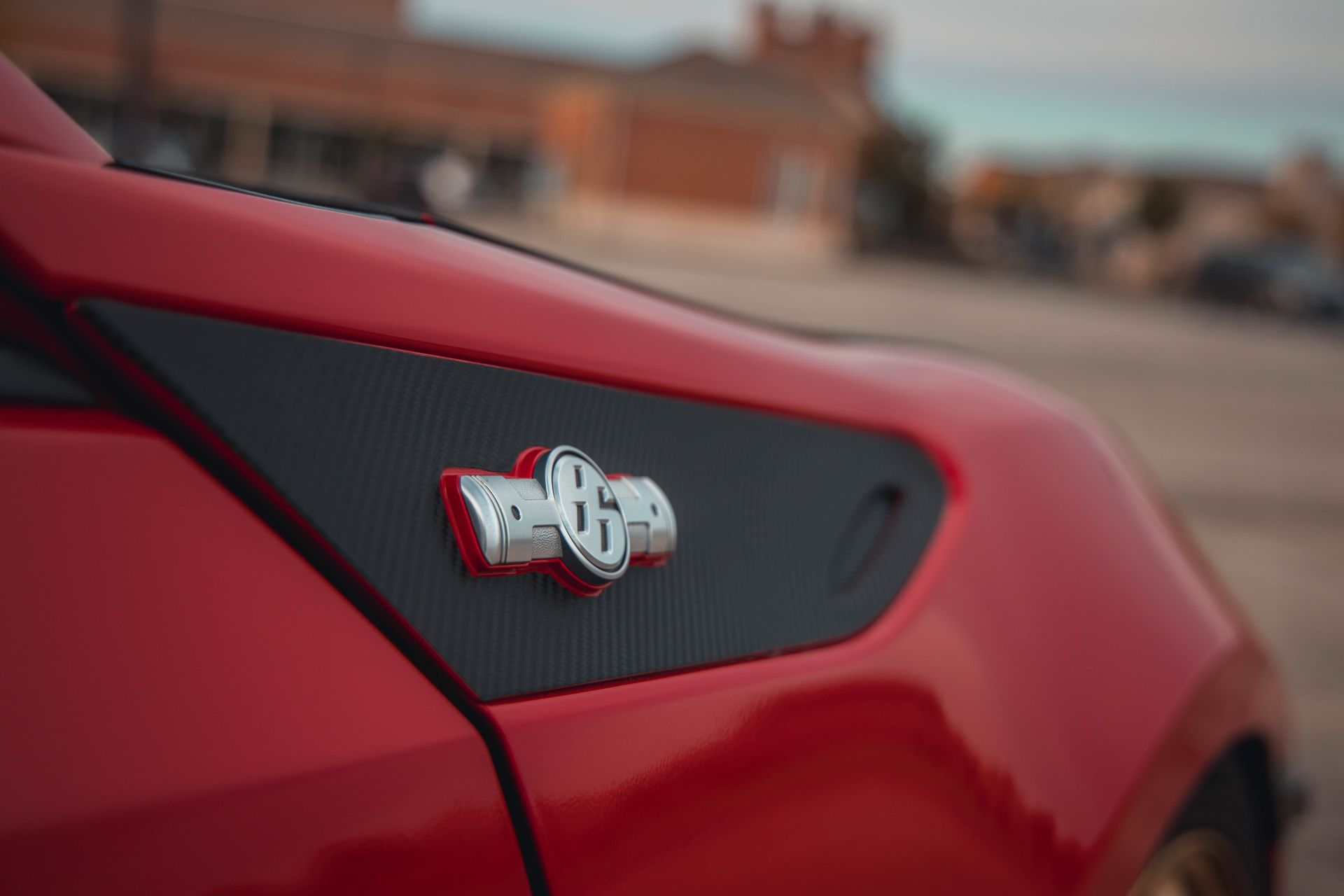 Detailed close-up of a red sports car badge highlighting brand and elegance.