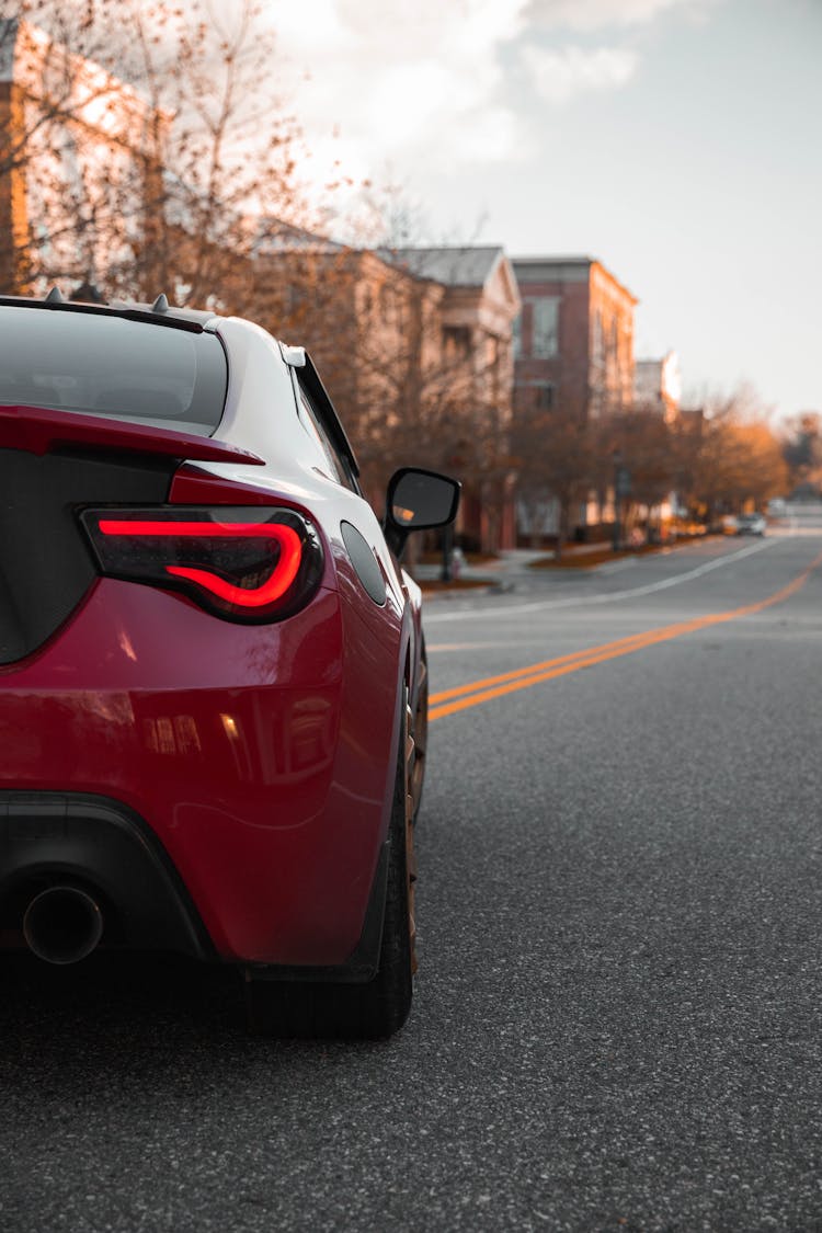 Rear View Of Red Car Parked In Middle Of Town Street