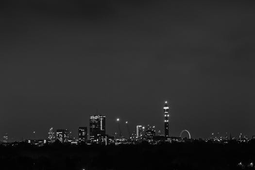 Captivating black and white photo of a city skyline featuring skyscrapers and urban lights at night.