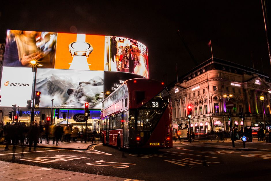 Vibrant nighttime view of a double-decker bus and illuminated billboards at Piccadilly Circus, London.