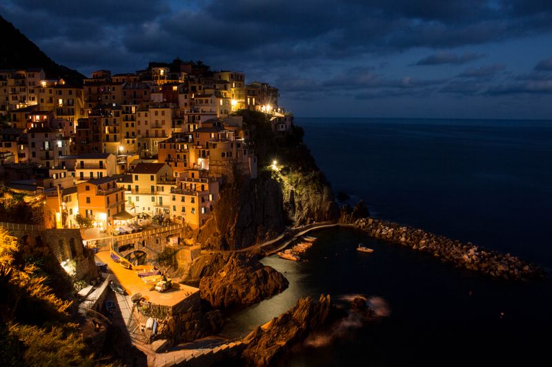 Manarola noaptea, cu luminile satului reflectate în apă