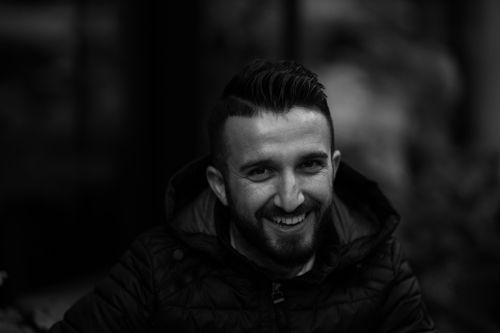 Free Captivating black and white portrait of a man with facial hair, smiling warmly against a blurred background. Stock Photo