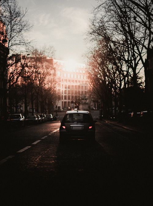 Free Street scene in Paris with cars silhouetted against the twilight sky, capturing the city's urban charm. Stock Photo