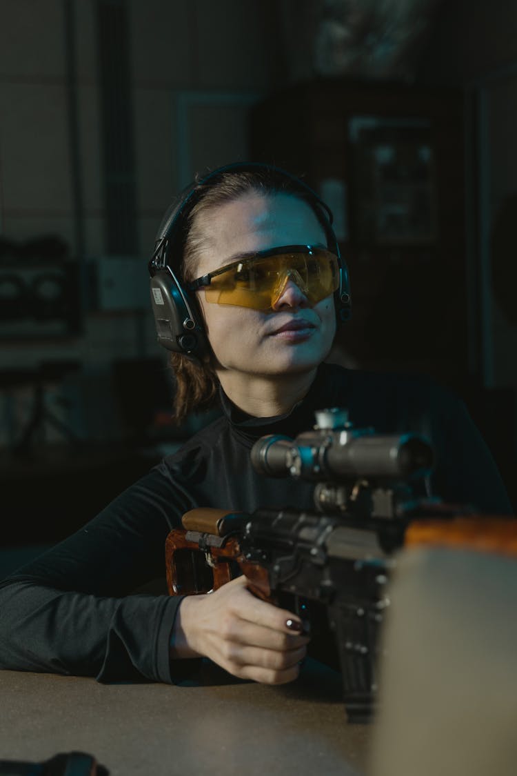 Woman In Black Long Sleeves Holding A Rifle