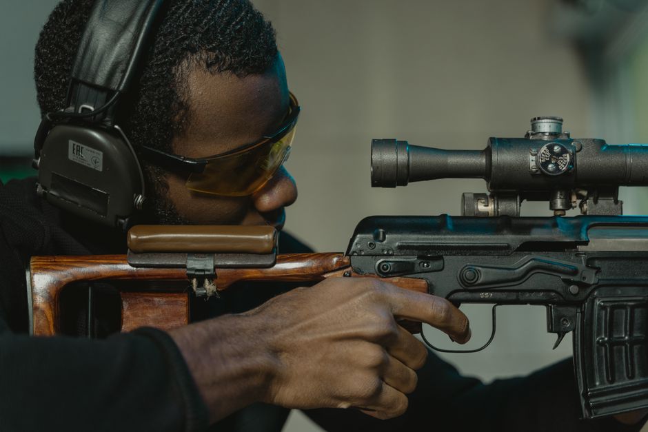 射撃場で目と耳を保護した男がライフルを構えているクローズアップ。
