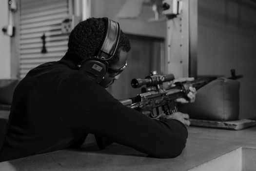 Grayscale Photo of a Man in Black Long Sleeves Holding a Rifle