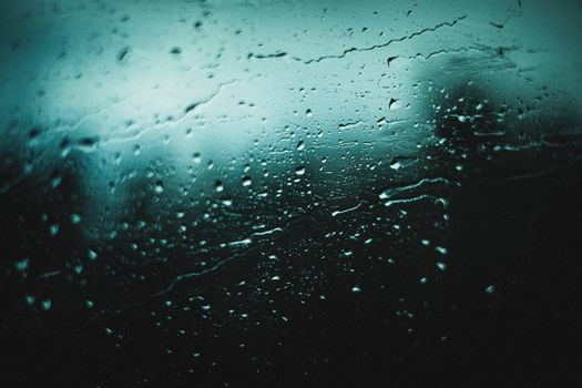 Close-up of raindrops on a glass window showcasing an abstract pattern with moody lighting.