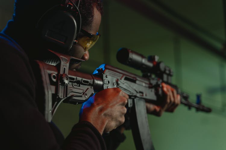 A Man Aiming A Rifle Using A Scope