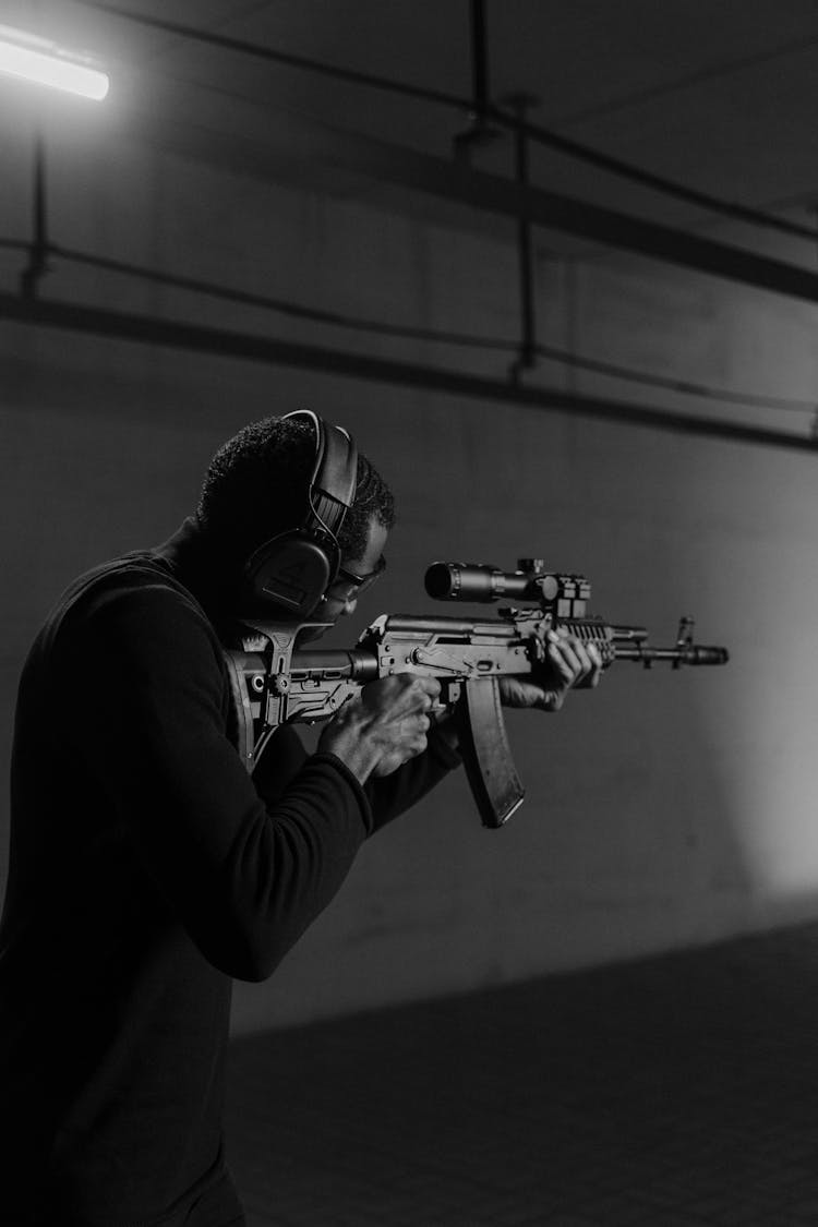 A Man Aiming An Assault Rifle With A Scope