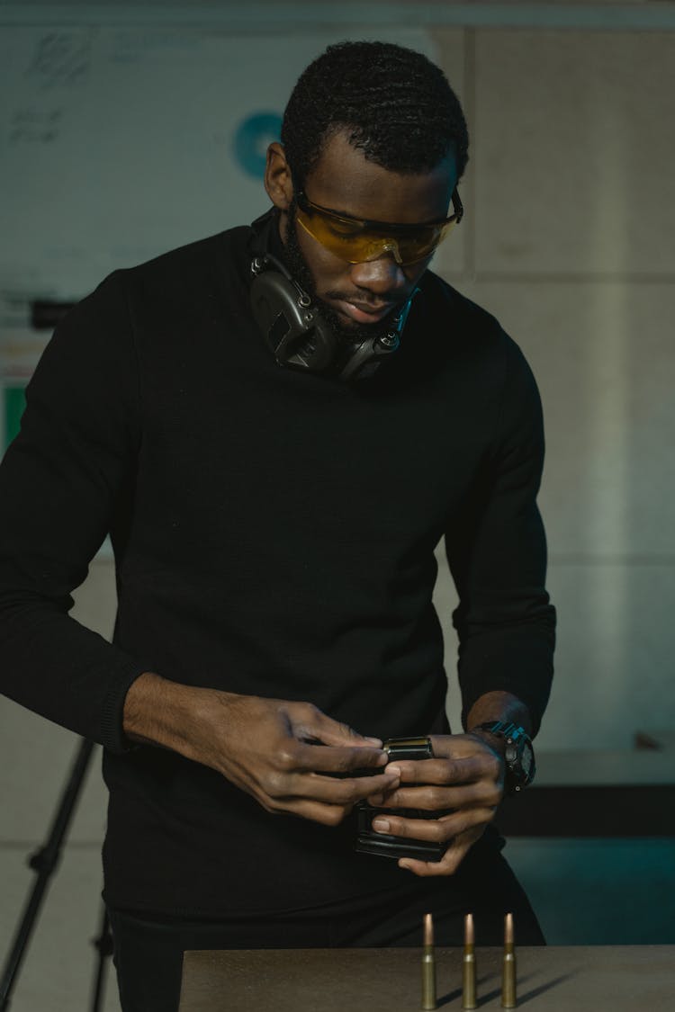 Man In Black Long Sleeves Holding A Bullet