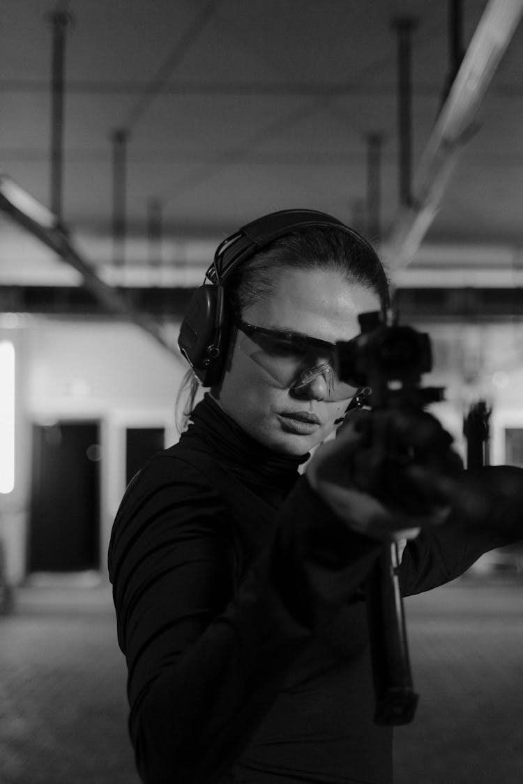 Woman Holding A Black Rifle In Grayscale Photography