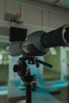 A high-precision telescope mounted on a tripod indoors, suitable for research or surveillance.