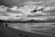 Grayscale Photo of Person Standing at the Beach