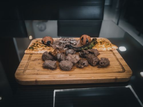 Free Tasty grilled meat pieces with green chili and onion slices on wooden cutting board on table Stock Photo