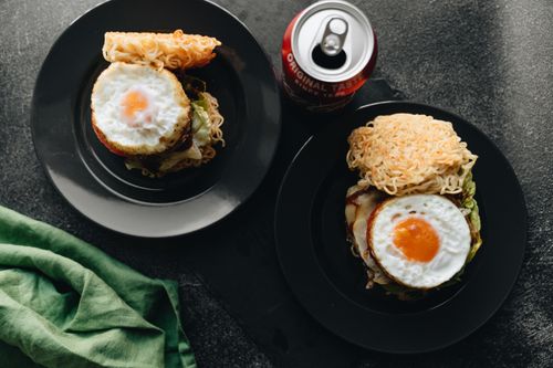 Free Top view of ramen burgers with fried eggs and a soda can offering a delicious twist on classic snacks. Stock Photo