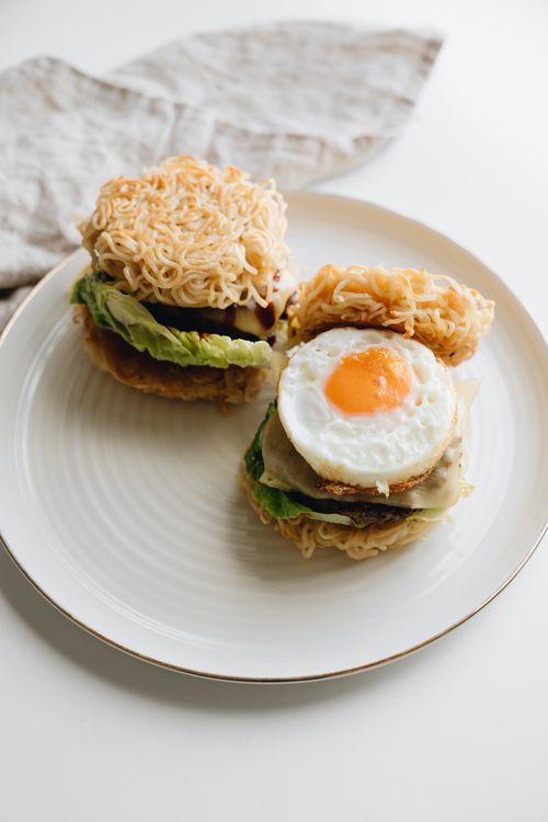 Free Delicious ramen burgers with lettuce and a sunny-side-up egg on a ceramic plate. Stock Photo