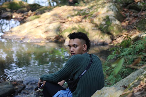 A Man Sitting Near a Body of Water