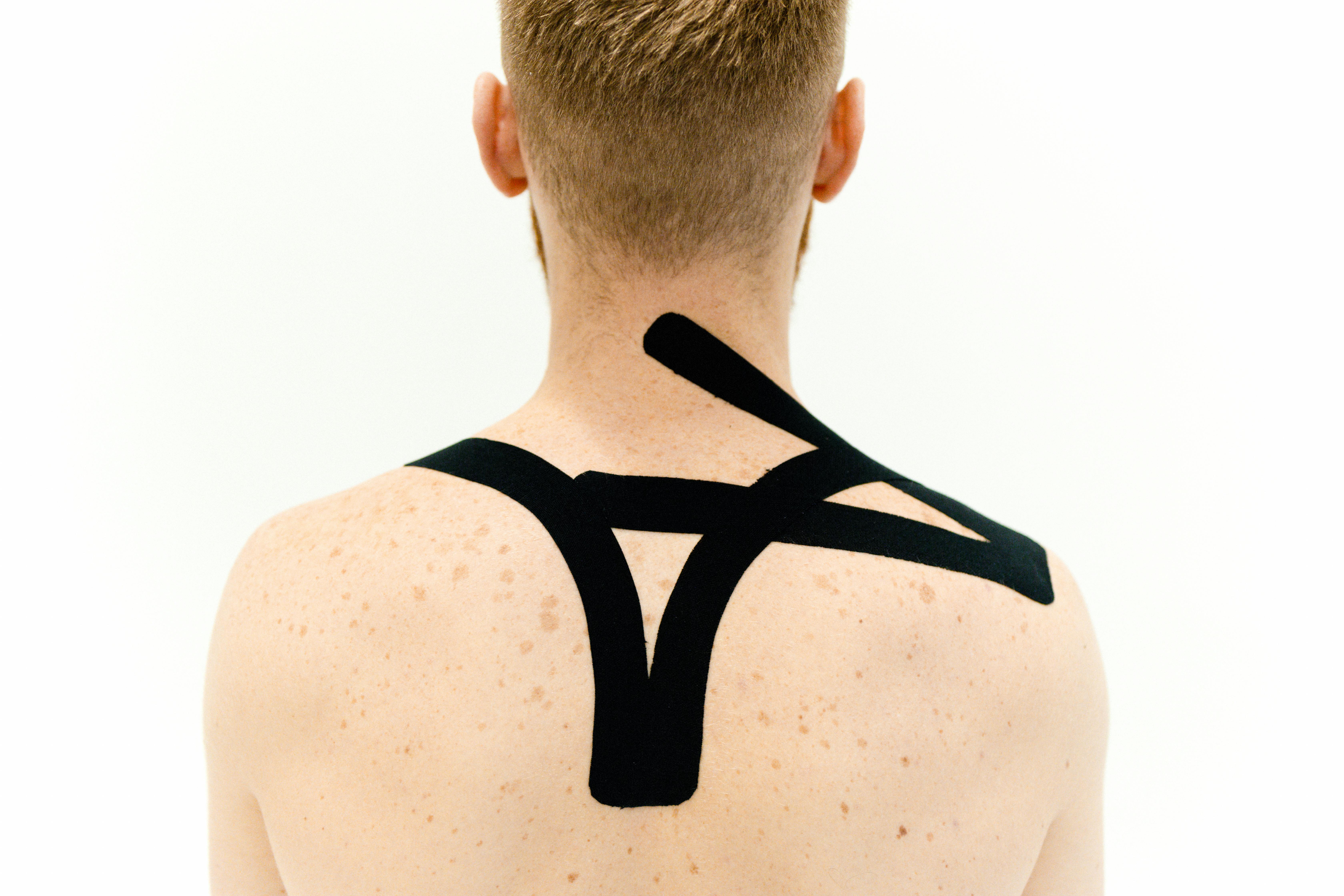 a man with black kinesio tapes on his upper back