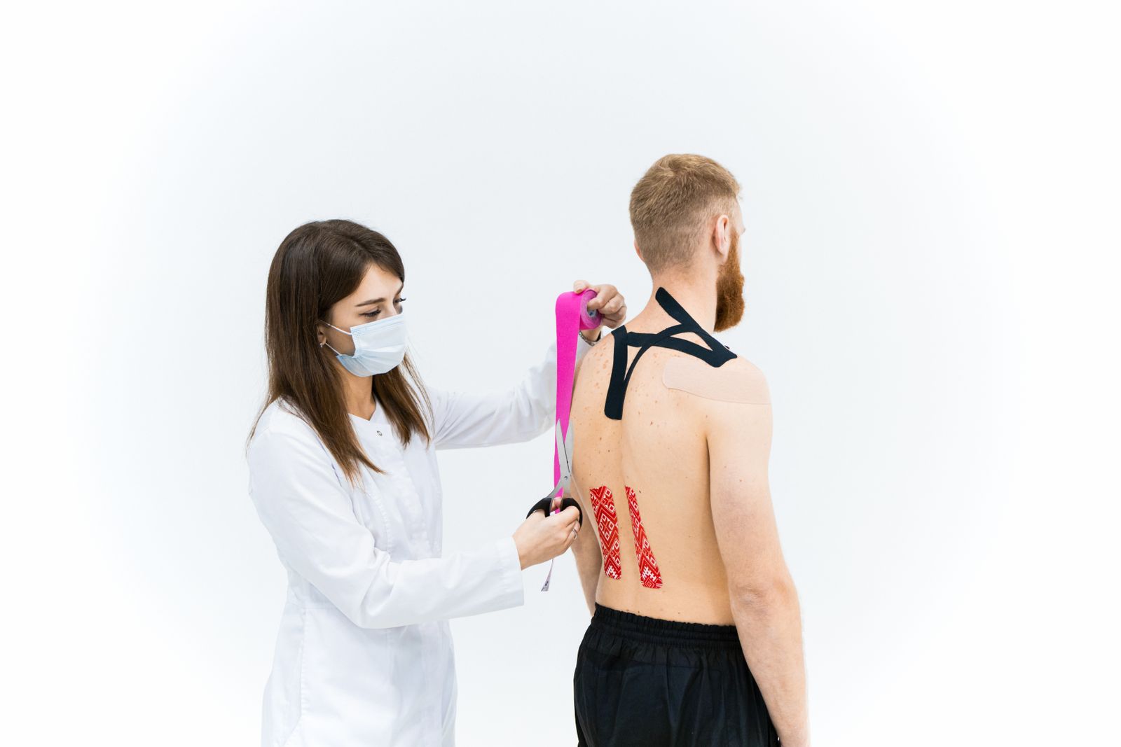 Bright physiotherapy room with a clinician supporting a person through shoulder mobility work