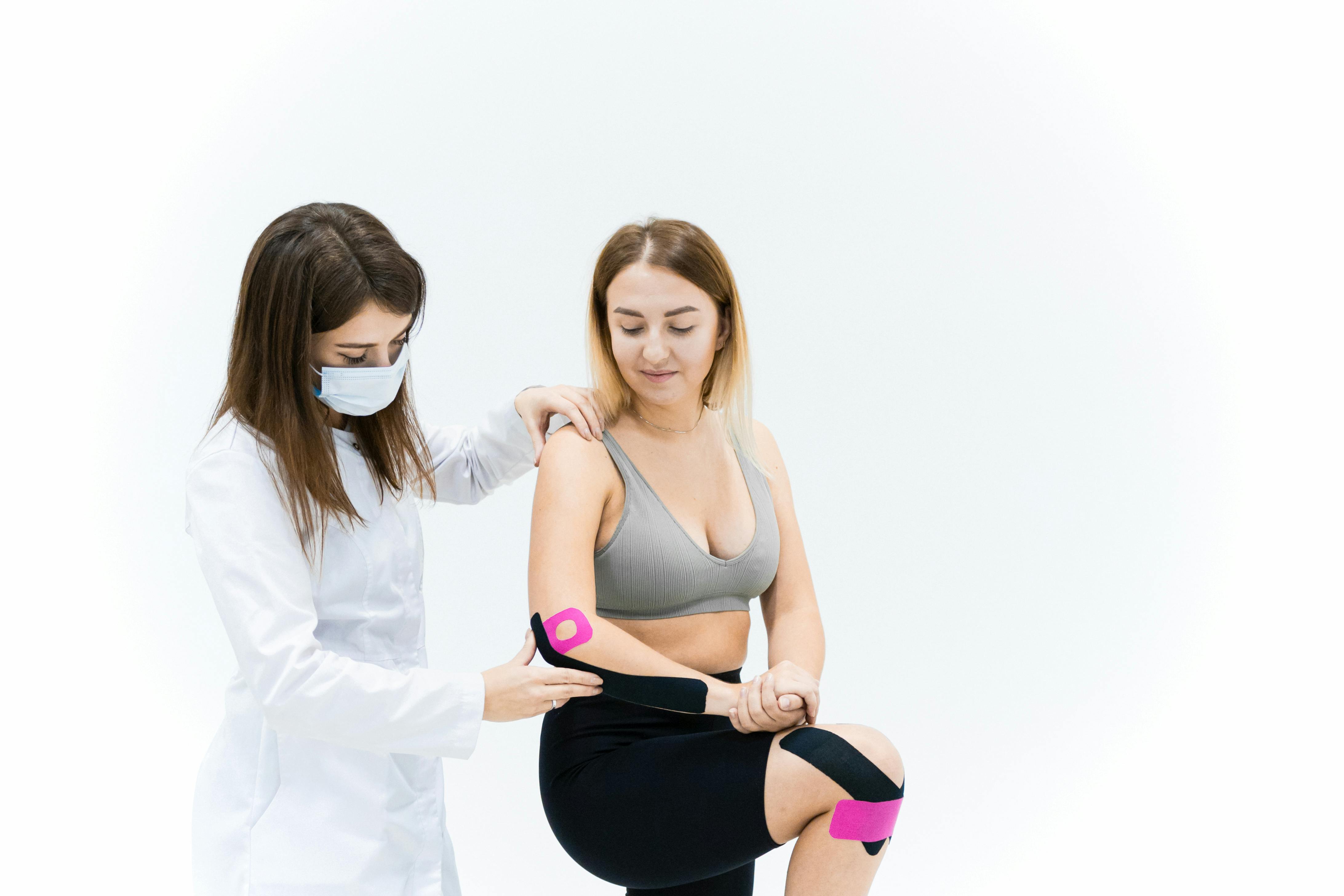 a medical practitioner treating a woman with kinesio tape