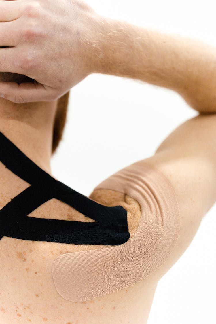 A Man With Kinesio Tapes On His Upper Back And Shoulder