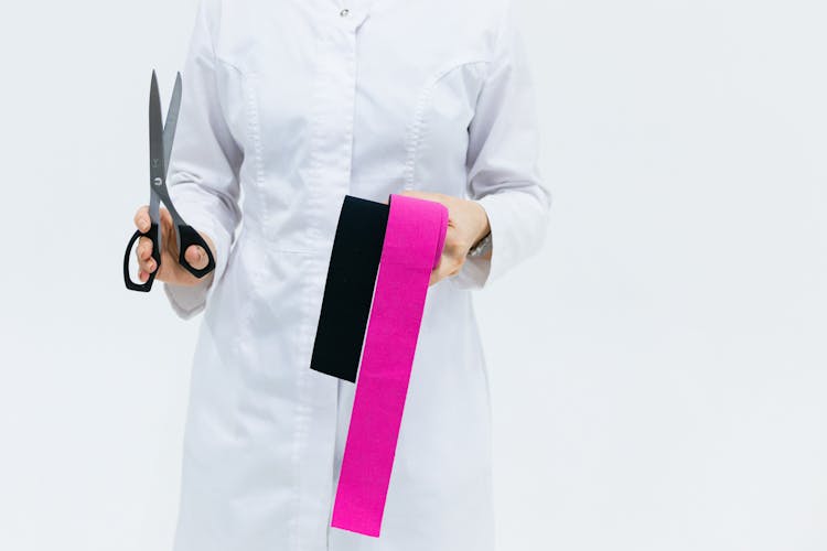 A Person Holding A Scissor And Kinesio Tapes