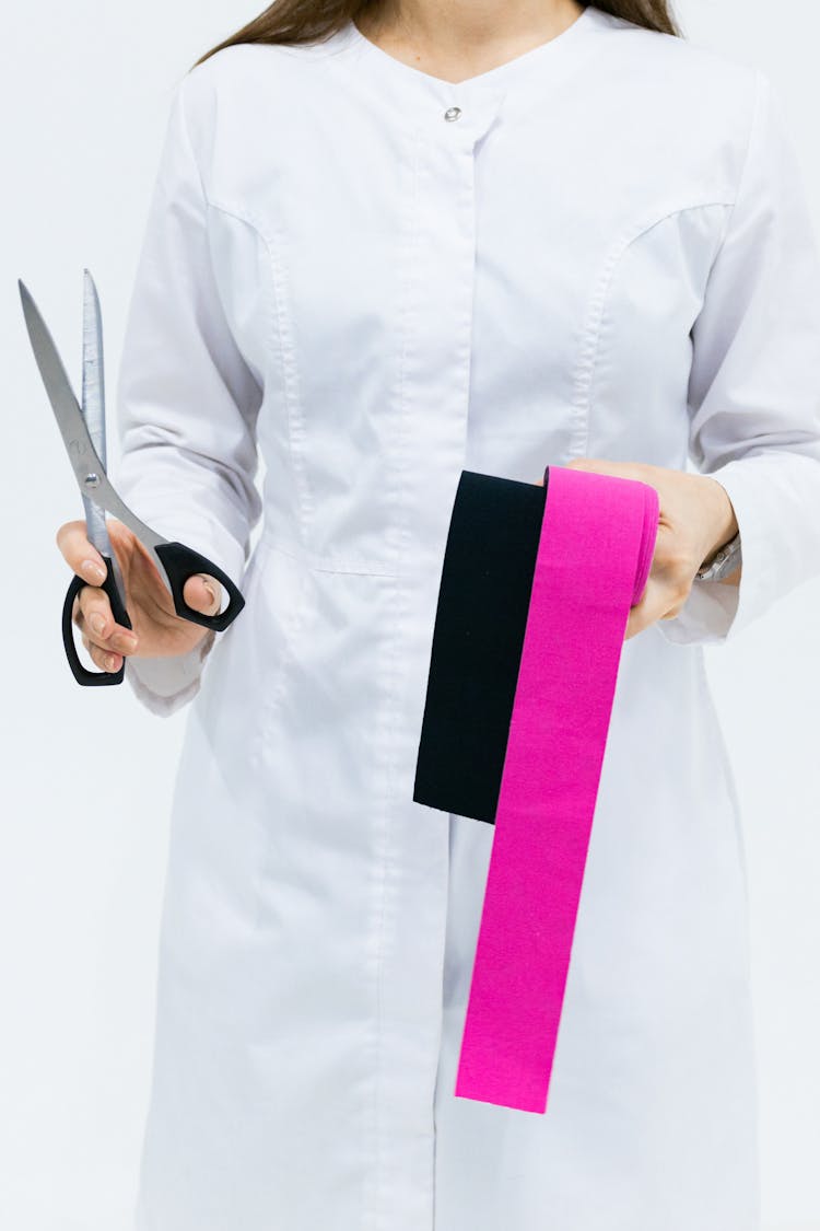 A Medical Person Holding A Scissor And Kinesio Tapes