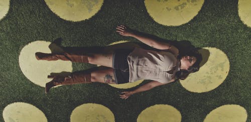 Woman lying on green meadow with grass