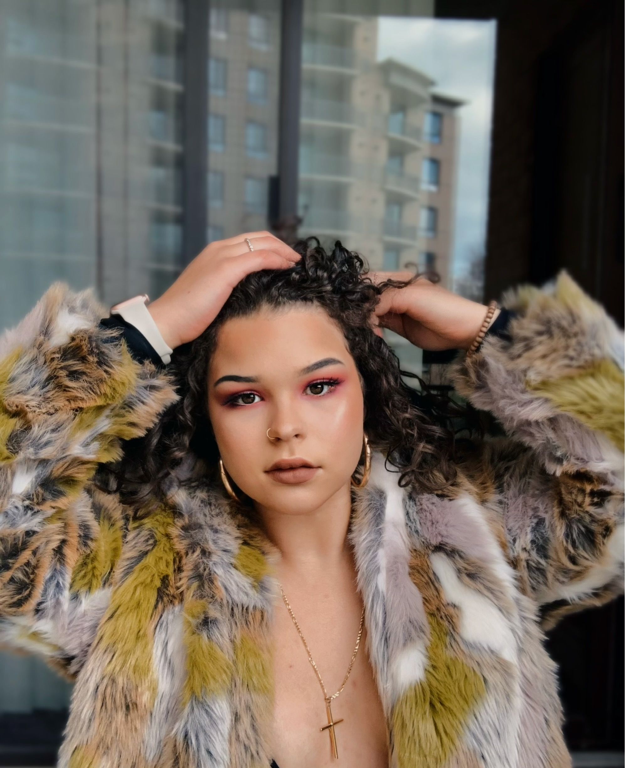 Elegant portrait of a woman in a luxury fur coat against a cityscape, exuding glamour and confidence.