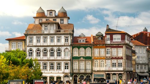 Free Vibrant historic building facades in Guimarães, Portugal with pedestrians in public space. Stock Photo