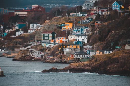 Facades of modern dwelling housing complex on dry mount against wavy ocean in town in daylight