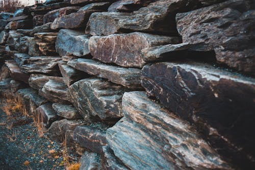 Rows of rugged gray stones with uneven surface on barren terrain with faded grass in fall