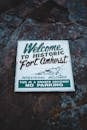 Rectangular shaped vintage signboard with Fort Amherst title and illustration on rugged surface with lichen