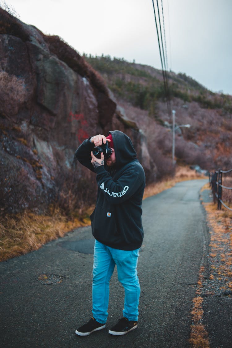 Photographer On Road Taking Photo Of Mountain On Digital Camera