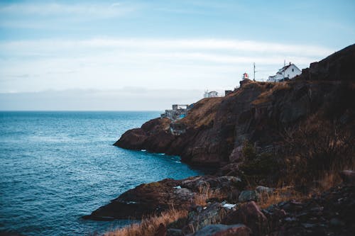 Free Picturesque scenery of houses placed on rocky cliffs near rippling water of ocean in daytime Stock Photo