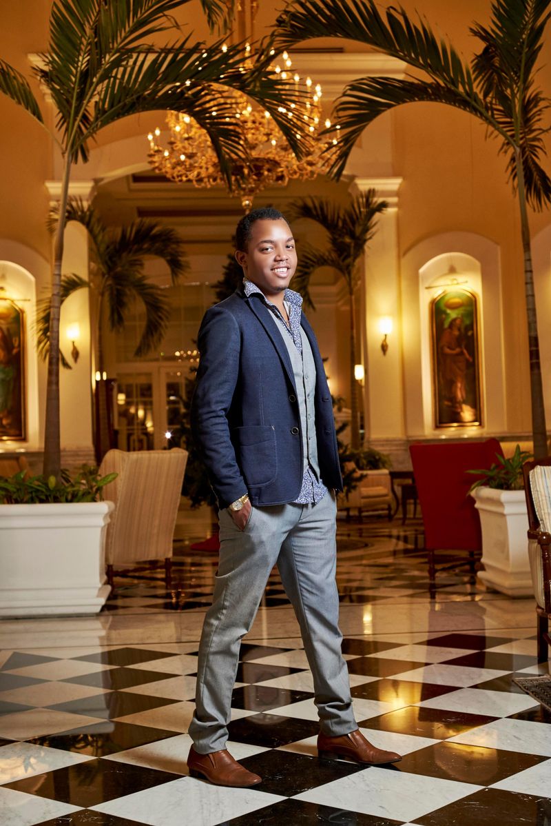 Stylish man in a blazer posed confidently in a luxurious hotel lobby with chic decor.