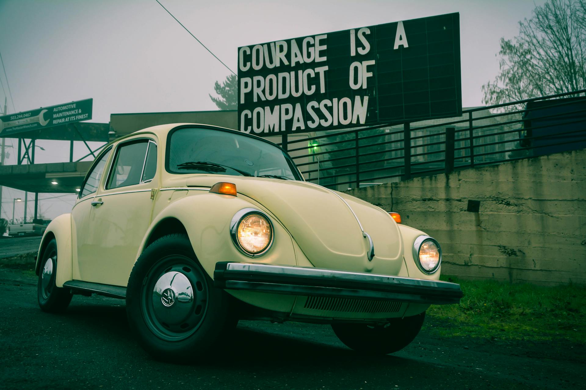 A classic Volkswagen Beetle parked on a foggy Portland street with an inspiring quote in the background.