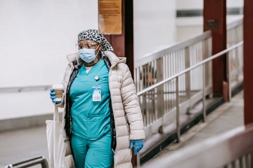 Black female nurse in uniform and protective mask on street