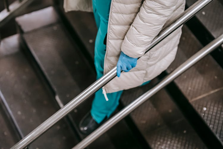 Woman In Medical Uniform Walking Down On Metal Steps