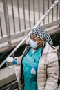 Black female nurse with paper cup going down to underground station