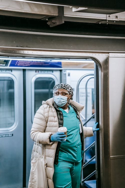 Black nurse in face mask exiting metro train