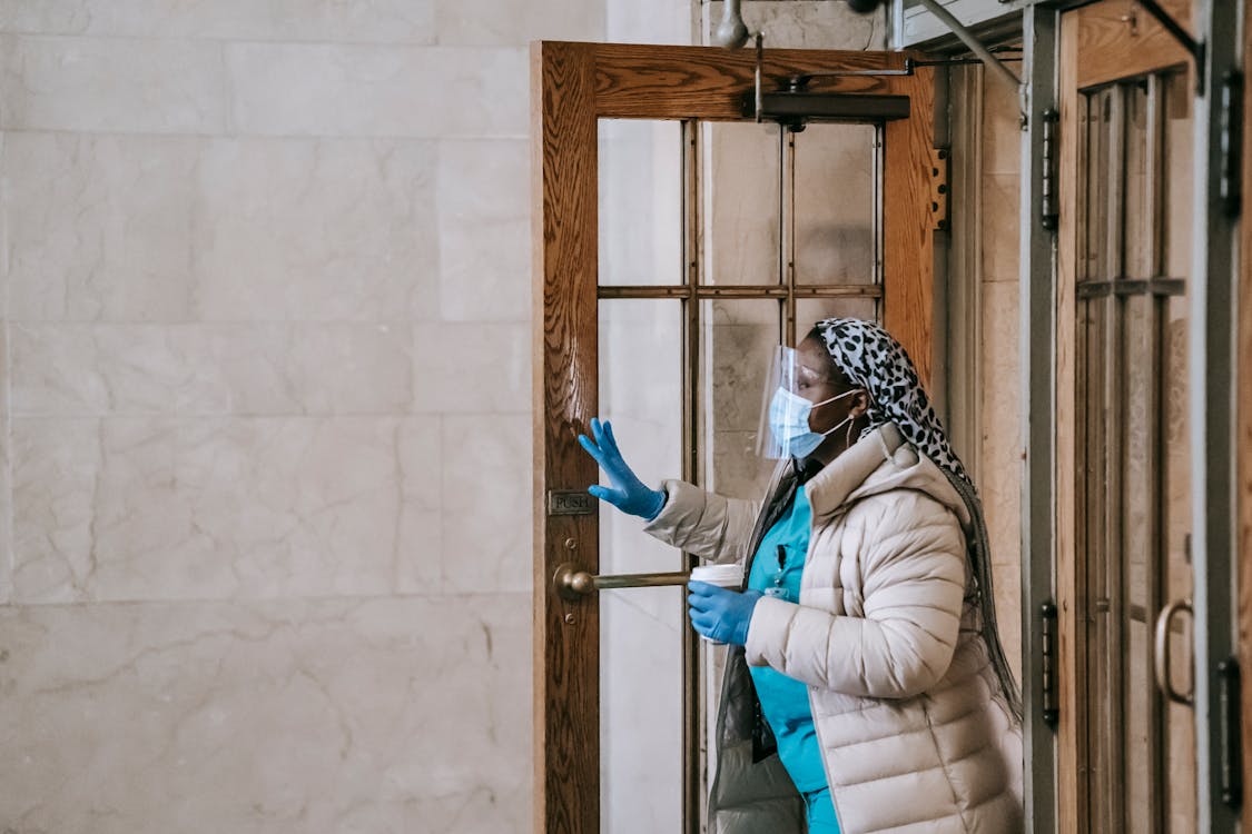 Free Black nurse in respirator and gloves leaving modern building Stock Photo