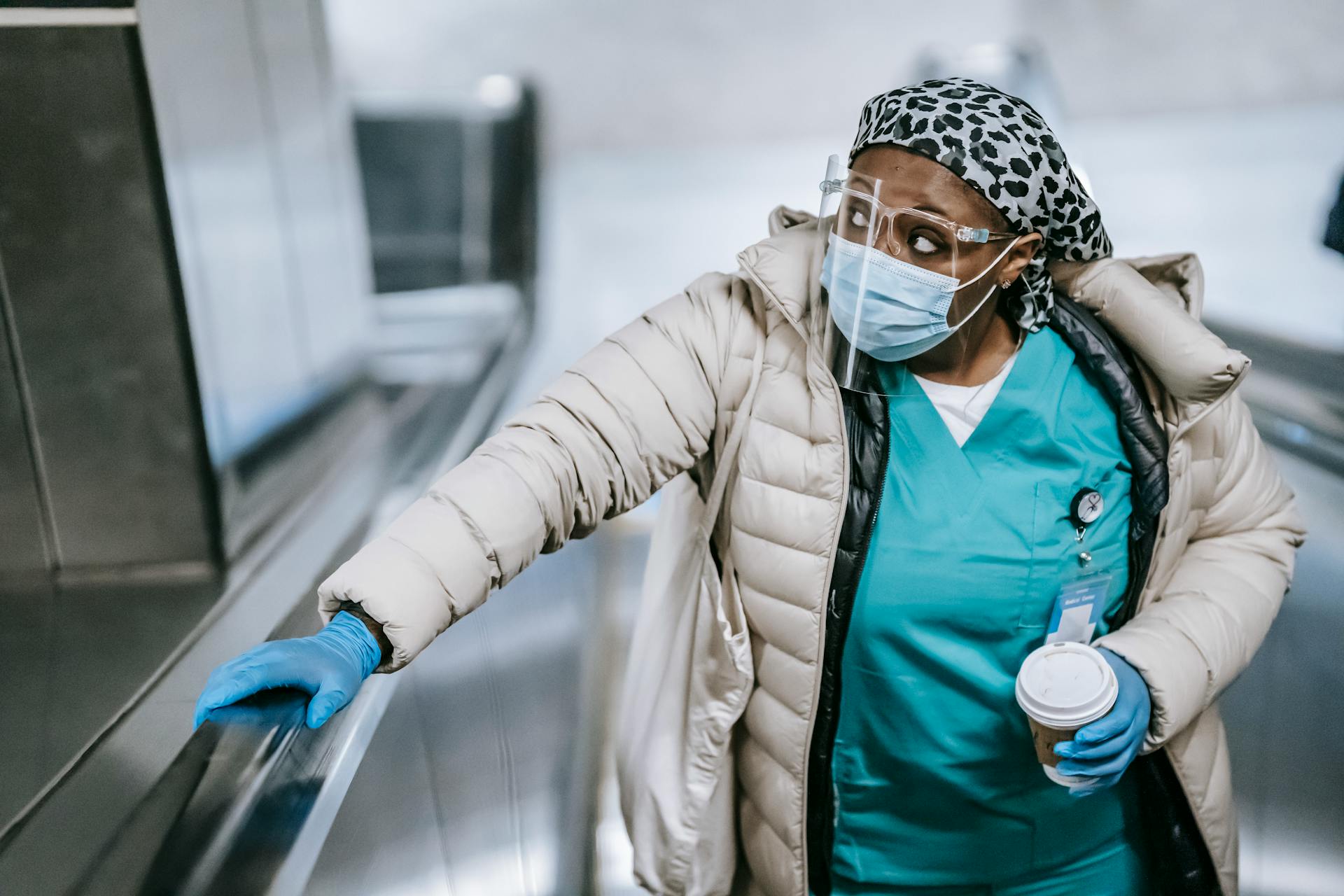 Black nurse riding escalator in metro station