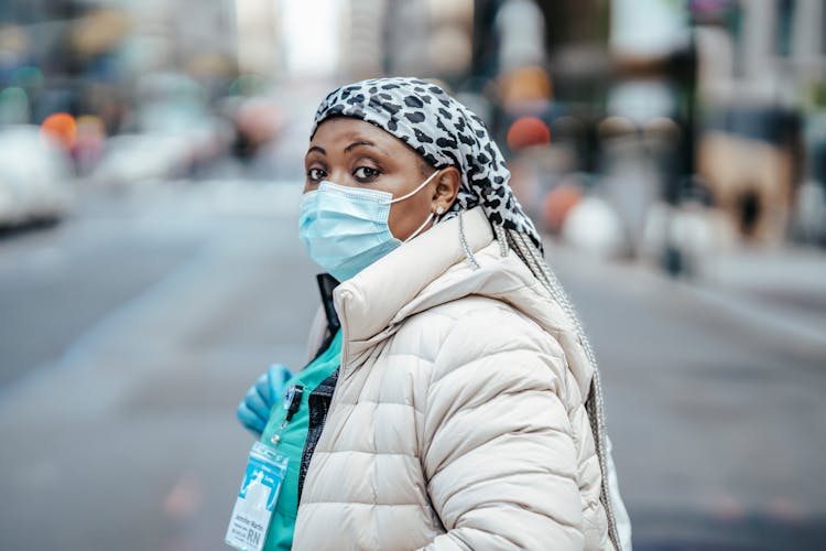 Black Nurse In Mask Crossing Road In Urban City