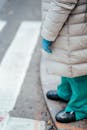 From above side view of crop anonymous female medic in sterile glove and outerwear standing near asphalt road in town